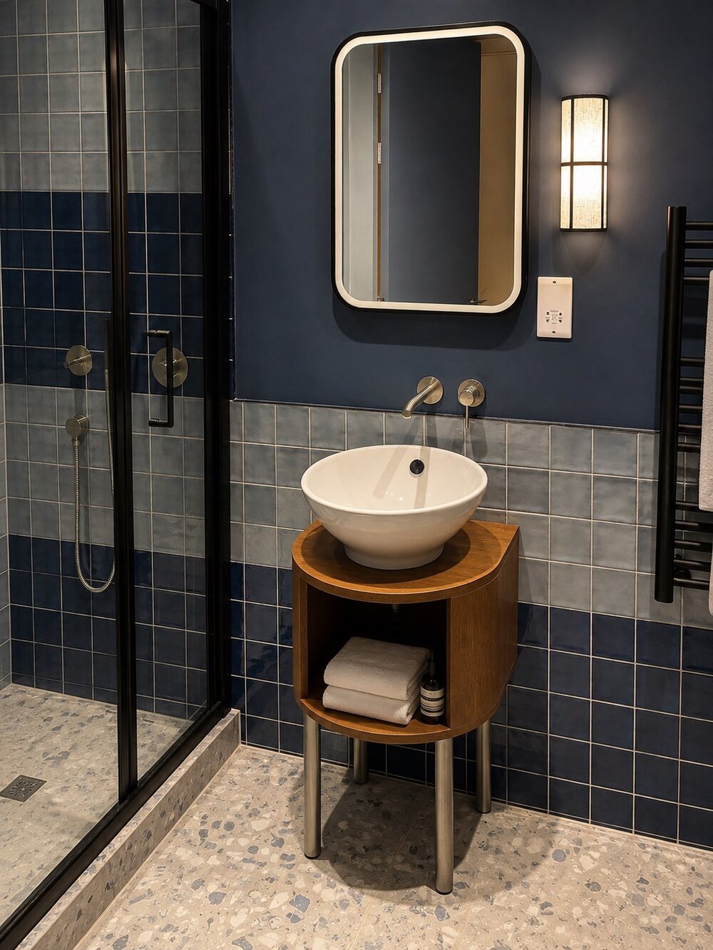 A bathroom at The Bolton, in deep blue tile with a brass-framed mirror
